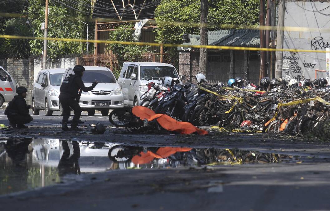 Members of a police bomb squad inspect the wreckage of motorcycles at the site where an explosion went off outside a church in Surabaya, East Java. Photo: AP