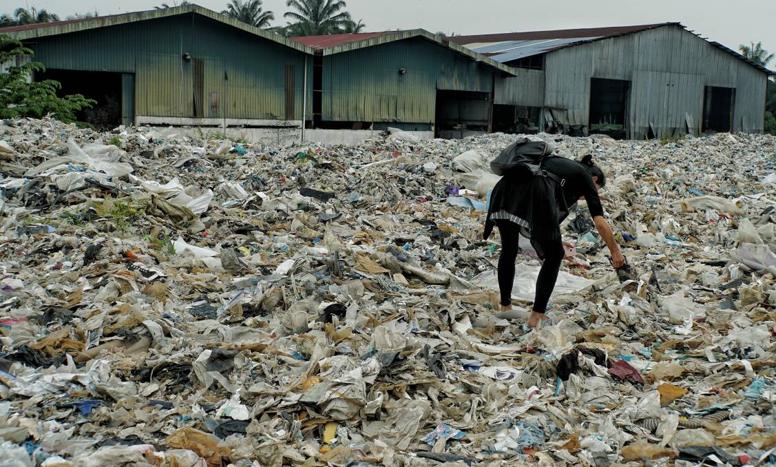 A member of the Kuala Langat environment NGO picks up  plastic waste at a shuttered illegal plastic recycling factory in Jenjarom.  Photo: Amelia Rosa