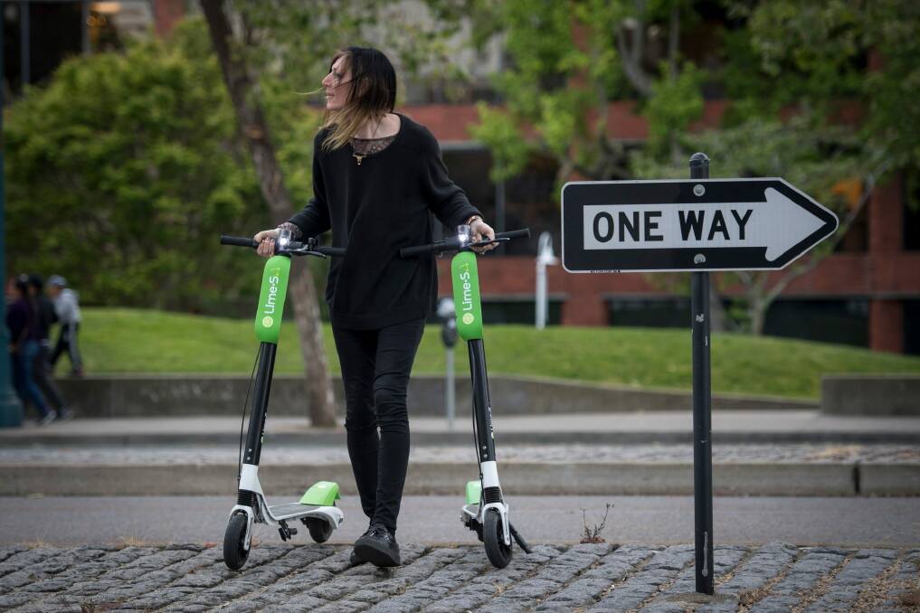 Livia Looper pushes LimeBike scooters in San Francisco, California, in May this year.  Photo: David Paul Morris/Bloomberg.
