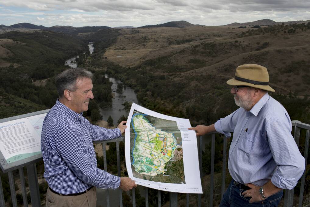 Riverview director David Maxwell, left, and consultant Tony Adam, at Shepherd's Lookout looking over the Murrumbidgee River and the area to the right to be developed for 11,500 homes and a conservation corridor. The pair, photographed in 2017, hold the development plan. Photo: Sitthixay Ditthavong