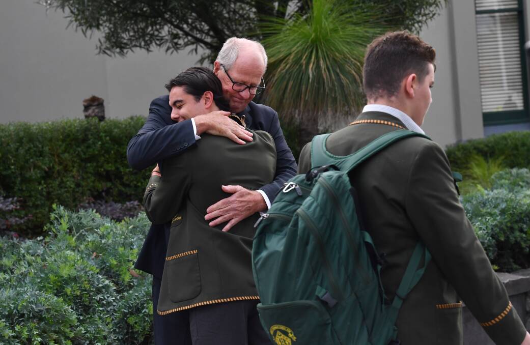 Rohan Brown hugs students upon his return to the school. Photo: Joe Armao