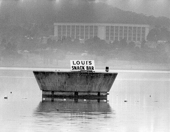 The Captain Cook Fountain, which has now reopened for business, was once temporarily renamed to promote a local takeaway. We understand this sign didn't last long. 
 Photo: ACT Heritage Library/Canberra Times collection. 