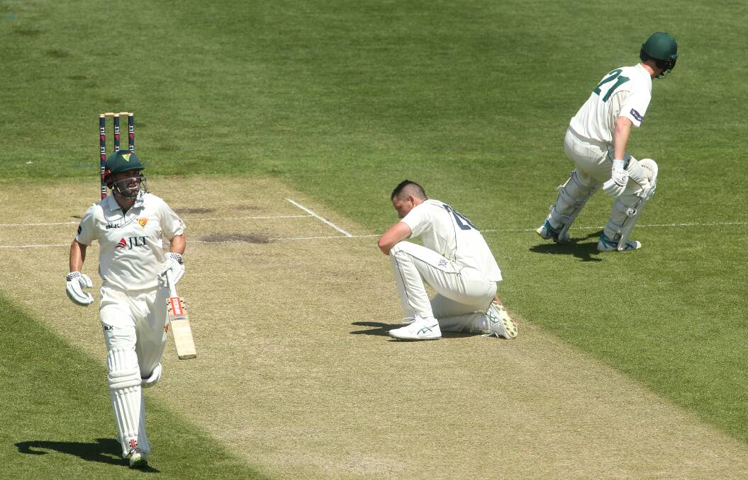 Grounded: Victorian bowler Chris Tremain (centre) goes down as Alex Doolan (left) and Jordan Silk of Tasmania take runs on day two. Photo: AAP