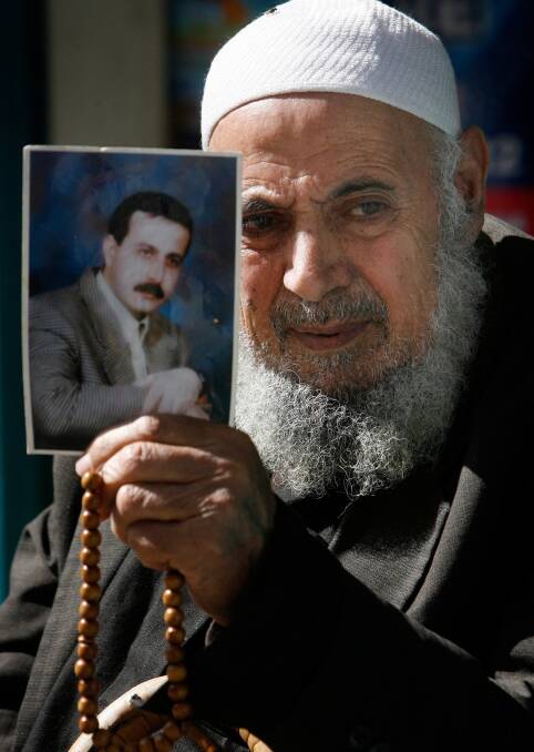  The father of assassinated senior Hamas military commander Mahmoud al-Mabhouh poses with a photograph of his son outside his family's house in February 2010. Photo: EPA