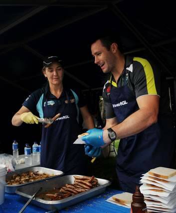 Capitals coach Carrie Graf and Raiders Brett White man the sausage sizzle. Photo: Colleen Petch