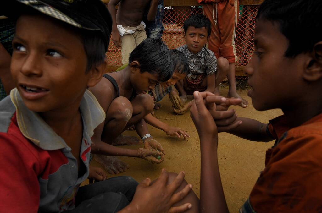 Rohingya children play in the mud with marbles in Kutupalong refugee camp after a monsoonal downpour. Photo: Kate Geraghty