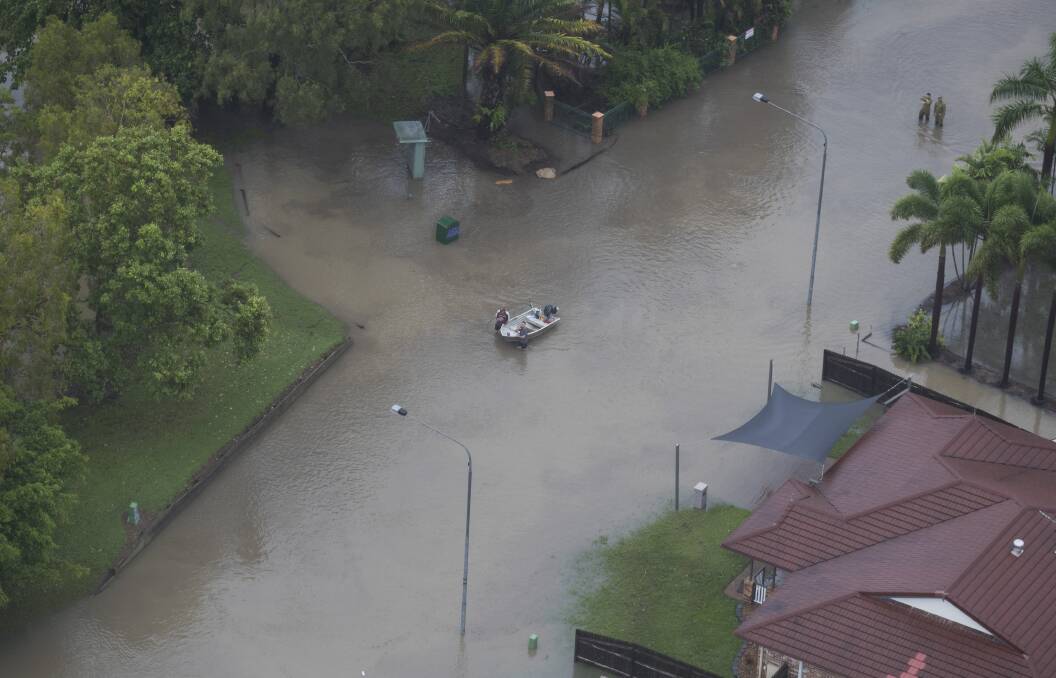 Residents leading a tinny through a flooded street in Townsville on Monday. Photo: Dave Acree - AAP