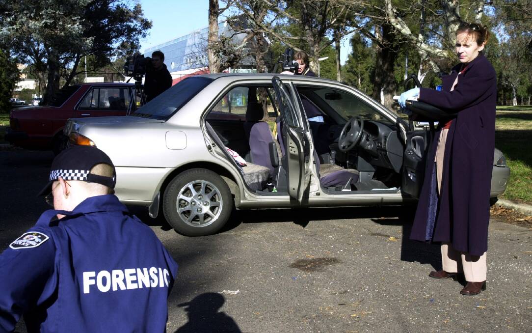 Police officers dusting for fingerprints inside a stolen car. Photo: Adam McLean