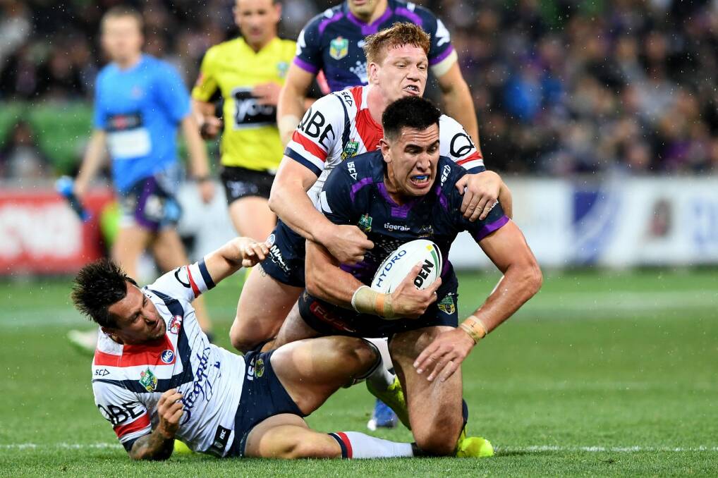 Near miss: Mitchell Pearce falls off the tackle with teammate Dylan Napa on Nelson Asofa-Solomona of the Storm. Photo: AAP