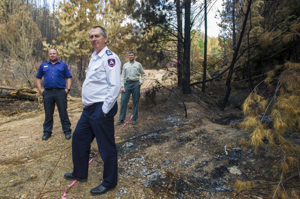 ACT Rural Fire Service senior rural liason officer, Chris Condon, ACT Rural Fire Service chief officer Joe Murphy and Parks and Conservation Service acting manager Adam McLachlan at the remains of burnt car that stated the Pierces Creek fire. Photo: Elesa Kurtz