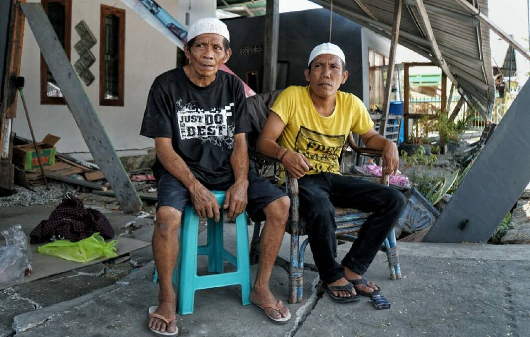 Tamrin, left, with his son Bobi in front of his damaged house. Photo: Amilia Rosa