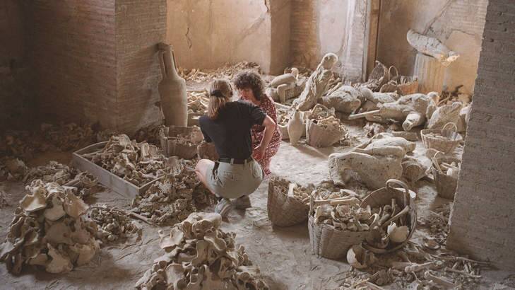 Dr Estelle Lazer, right, and a volunteer examine bones in Pompeii. Photo: Supplied