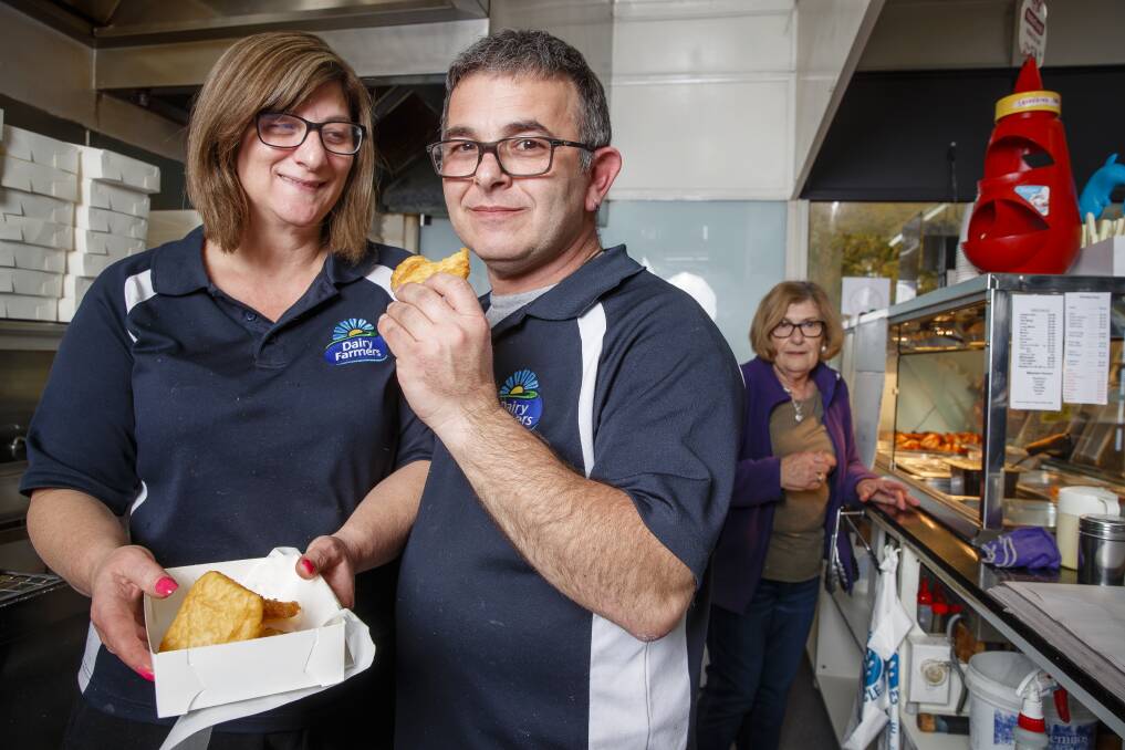 Hughes Takeaway owners Nita and Peter Dorizas with their much-loved potato scallops. Peter's mum Gina (in the background) is a crucial part of  the takeaway's potato scallop process. Photo: Sitthixay Ditthavong