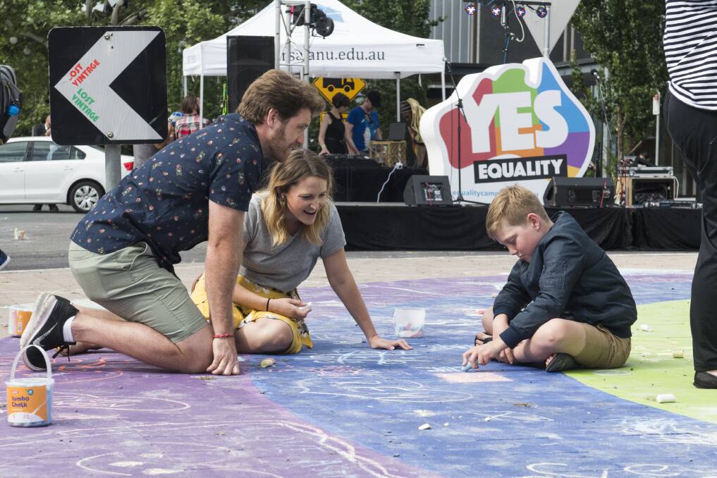 Daniel Little, Natalie Plummer, and Logan Little, 9, of Curtin take part in drawing with chalk on the rainbow roundabout. Photo: Elesa Kurtz