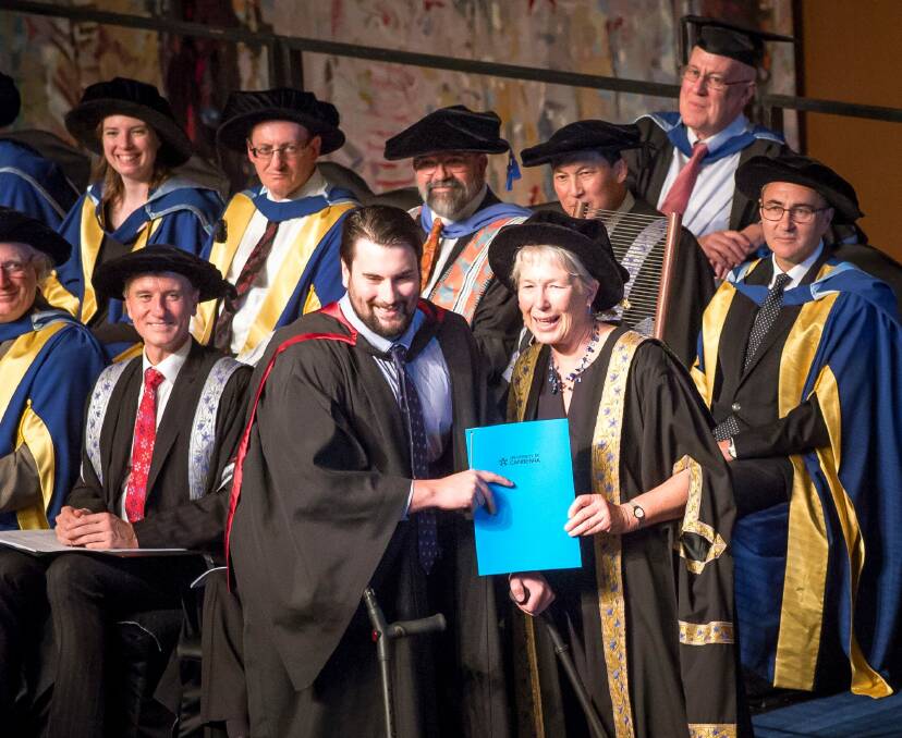 Canberra man and paraplegic Paul Jenkins accepts his degree from University of Canberra Deputy Chancellor Dr Sarah Ryan. Photo: Sitthixay Ditthavong