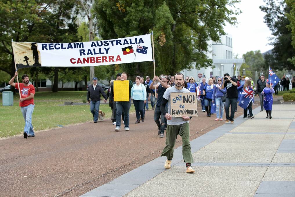 Protester Ben Keaney, centre, marches against supporters of Reclaim Australia in front of the National Library of Australia on Saturday. Photo: Jeffrey Chan