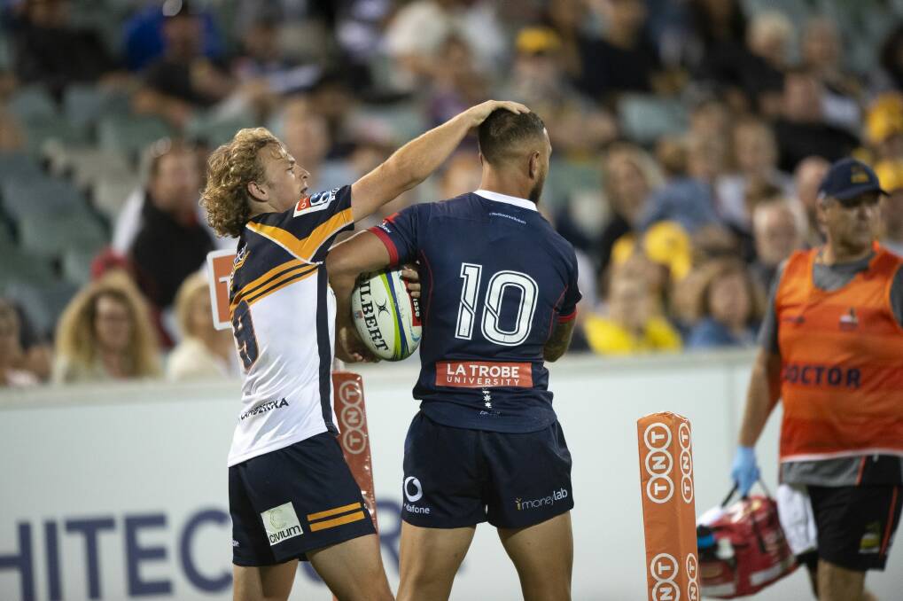 The Brumbies' Joe Powell and the Rebels' Quade Cooper exchange pats on the head as they fight for the ball. Photo: Sitthixay Ditthavong