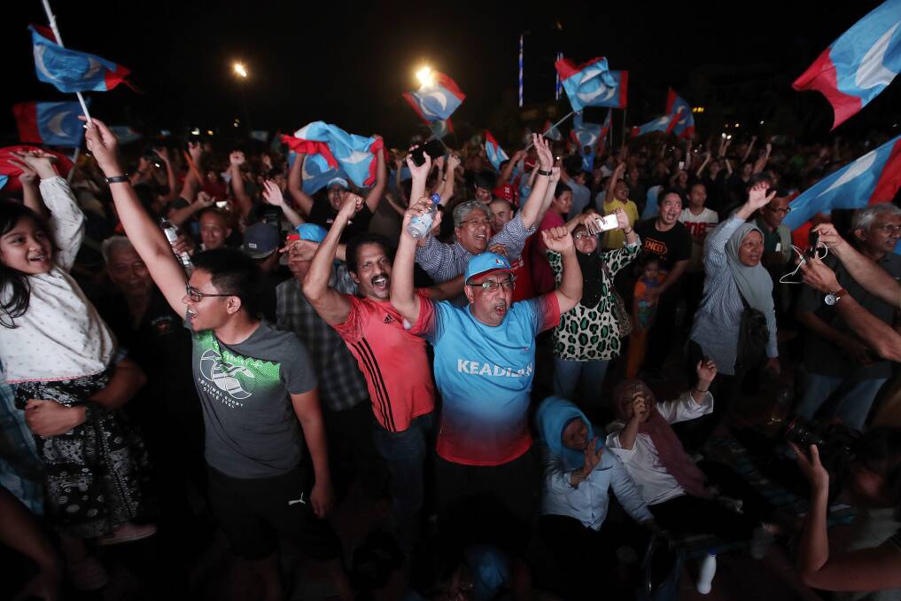 Opposition party supporters cheer and wave their party flags after Mahathir claimed victory. Photo: AP