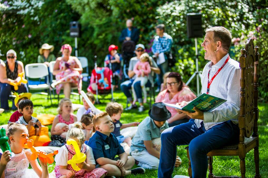 On the lawns of the Prime Minister's Lodge in Canberra, Rhys Muldoon reads to children at an event run by a charity serving Canberrans, Hands Across Canberra. Photo: Jack Mohr