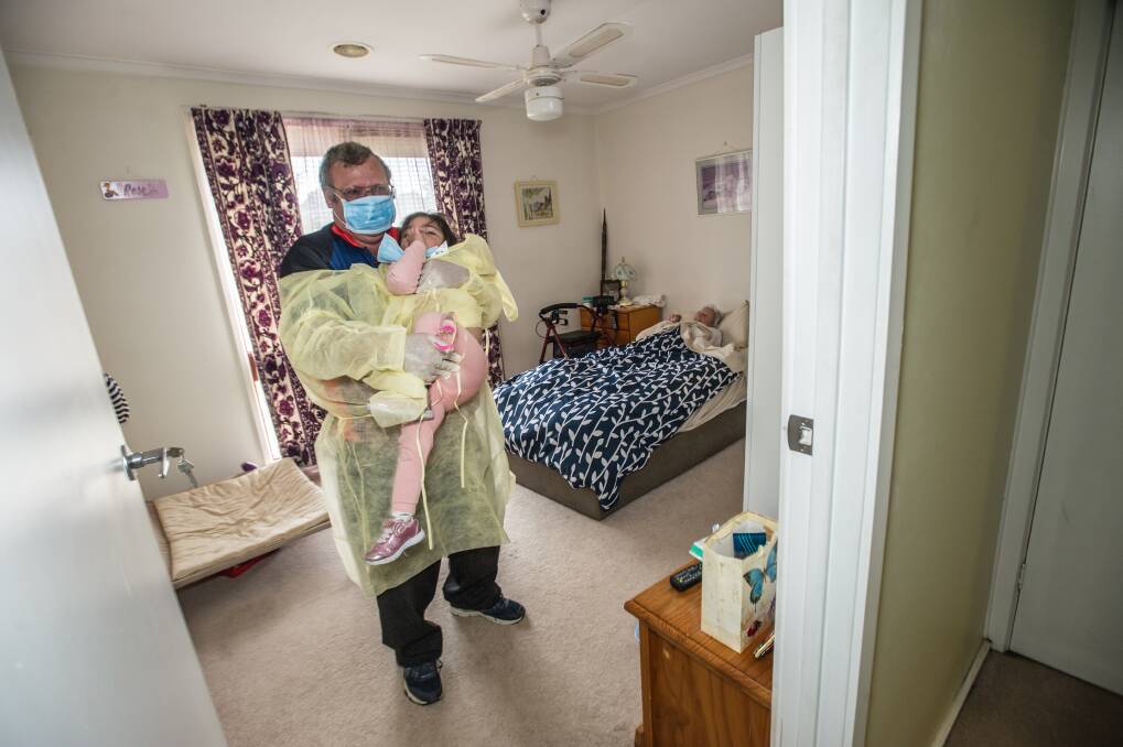 Peter Voelker and daughter, two year old Ellie, visit his sick mother in the bedroom of their family home after she was sent home from hospital. He is worried about  measures taken to prevent the spread of the strain of flu she has. Photo by Karleen Minney.