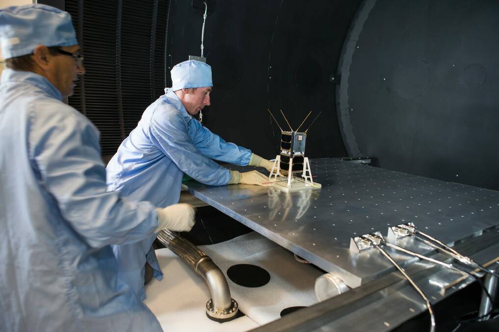 Mike Petrovic (left) and Bart Fordham from ANU load a CubeSat into the space simulator at the ANU Advanced Instrumentation and Technology Centre. Photo: Stuart Hay