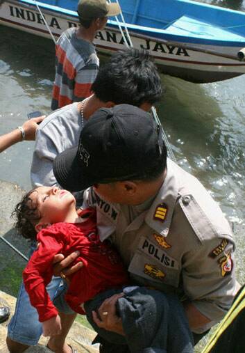 A police officer carries an unconscious child who was on the boat that capsized late on Tuesday after hitting a reef off the coast of Sukapura, in West Java. Photo: AFP