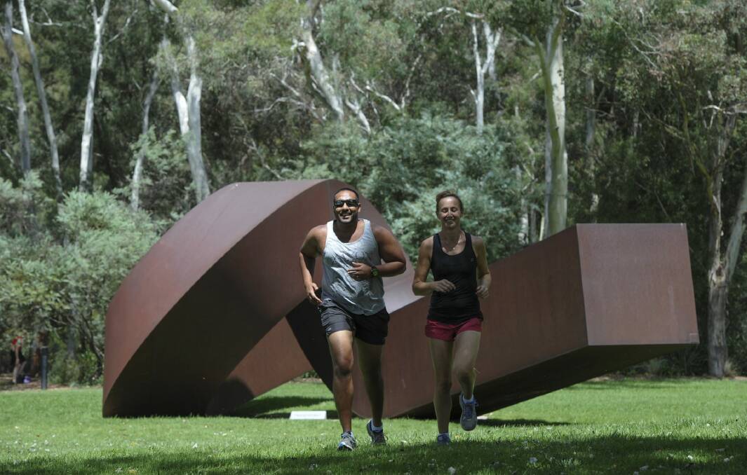 Lunchtime joggers, Link Perera of Kambah and Jodie Bijorac of Queanbeyan, run through the sculpture garden at the National Gallery of Australia. New figures show Canberra is the most active and cultured place in the country.  Photo: Graham Tidy