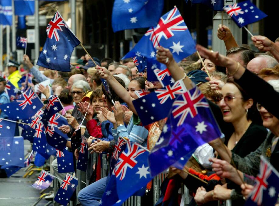 A flag-waving crowd on George Street, Sydney, as an Anzac Day march passes by.  Photo: Dallas Kilponen