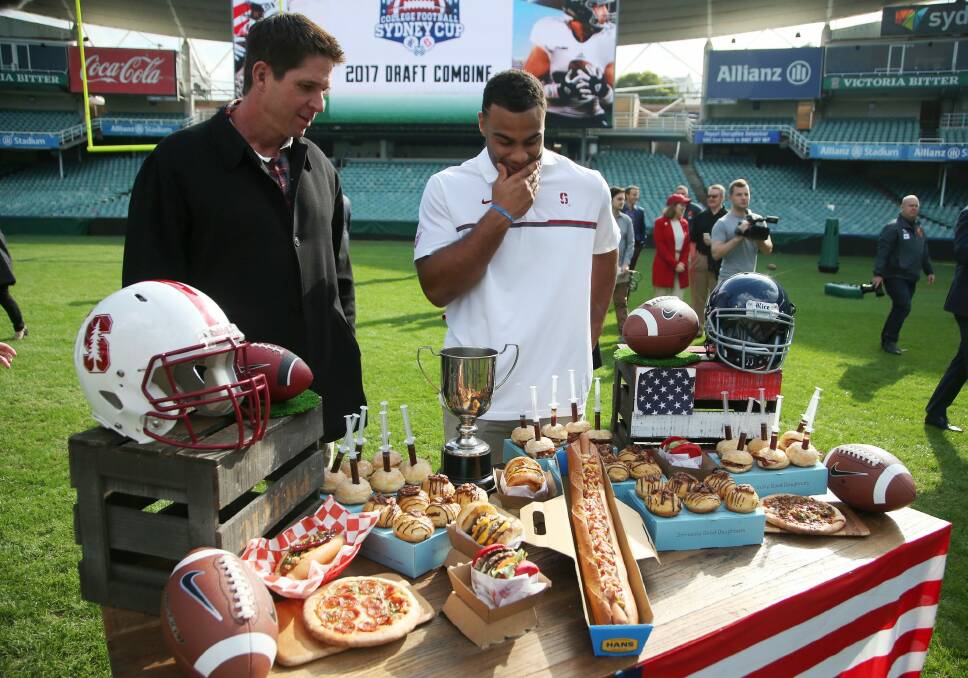 Feast of football: Three-time Super Bowl champion Ed McCaffrey (left) and Solomon Thomas look over a sample of American classics that will be available to fans in Sydney when the Stanford University take on Rice University in August. Photo: AP