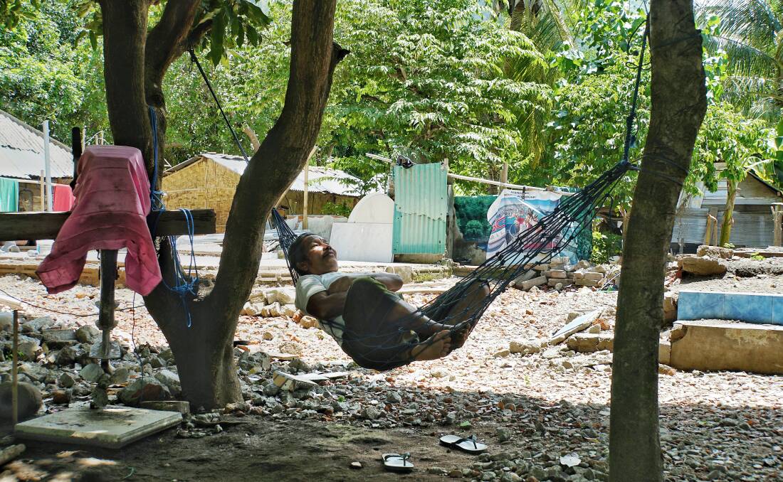 A villager from Nipah in North Lombok rests in a hammock in front of the ruins of what used to be his big family house. Photo: Amilia Rosa