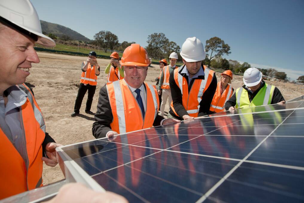 ACT Greens MLA Shane Rattenbury, Planning Minister Mick Gentleman and Daniel Radford lifting panels at the Williamsdale solar farm. Photo: Ricky Fuller 