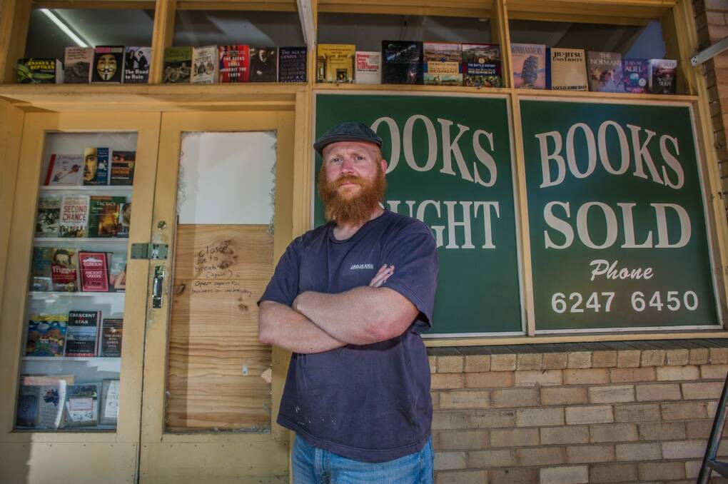 Book Lore bookshop owner Mike Johnson plans to replace a glass door this week smashed by thieves with a solid wooden door - and he would like local artists to paint a book-themed mural across it and the shopfront in a high-profile part of Lyneham. Photo: Karleen Minney