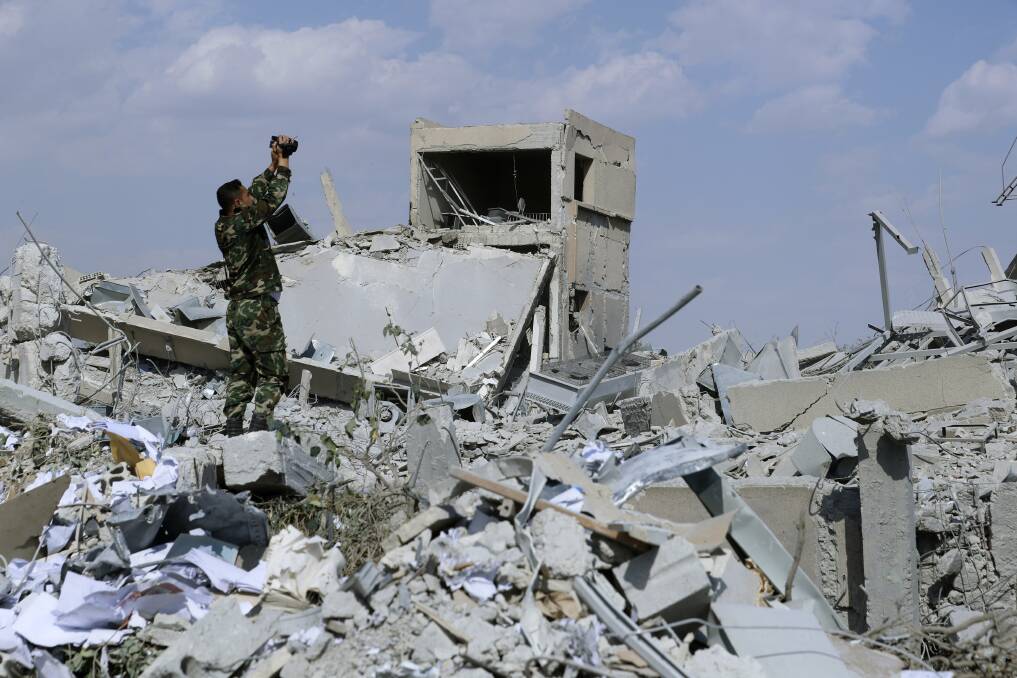 A Syrian soldier films the damage of the Syrian Scientific Research Centre. Photo: AP