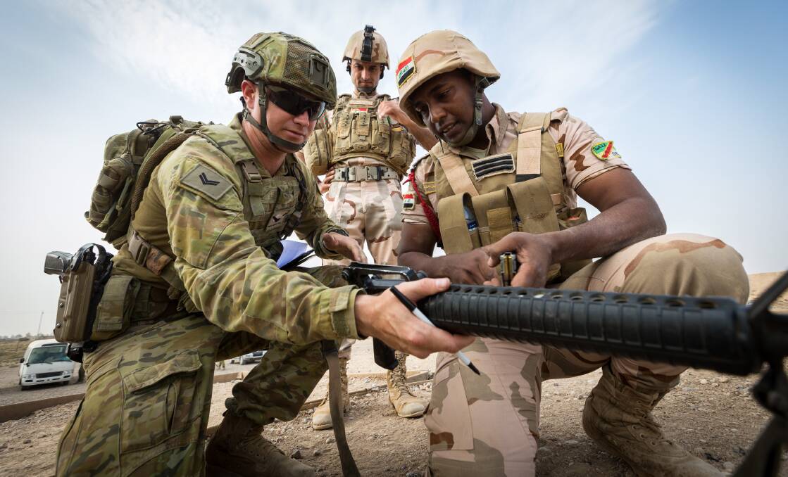 Australian Army soldier Corporal Eamon Baldwin helps an Iraqi Army soldier adjust his sights during a shooting competition at Taji Military Complex, Iraq. Photo: Corporal David Said