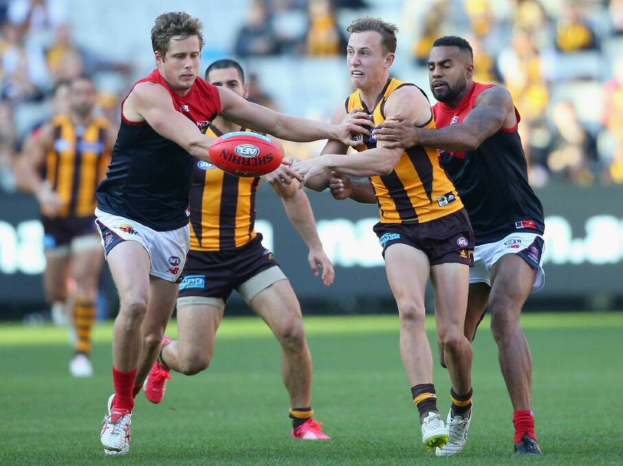 Billy Hartung  handballs while being tackled by Heritier Lumumba of the Demons. Photo: Getty Images