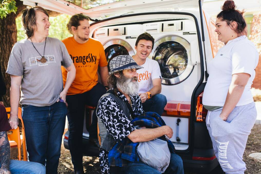 Queanbeyan local Haralg Haralg "Harry'' (seated) gets his clothes washed and dried by the Orange Sky Laundry van in Queanbeyan on Wednesday with (l-r) St Benedict's Community Centre manager Elaine Lollback, Orange Sky Laundry founders Lucas Patchett and Nic Marchesi, and centre user Sylvia Brumm.


 Photo: Rohan Thomson