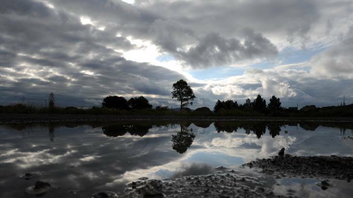 Rain clouds loom reflected in the water at the Jerrabomberra Wetlands car park. Photo: Graham Tidy
