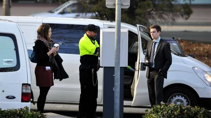 Sally Haysom and Will Atfield wait for the parking meter to be fixed by a technician before getting their tickets at the Civic Centre car park. Photo: Jay Cronan