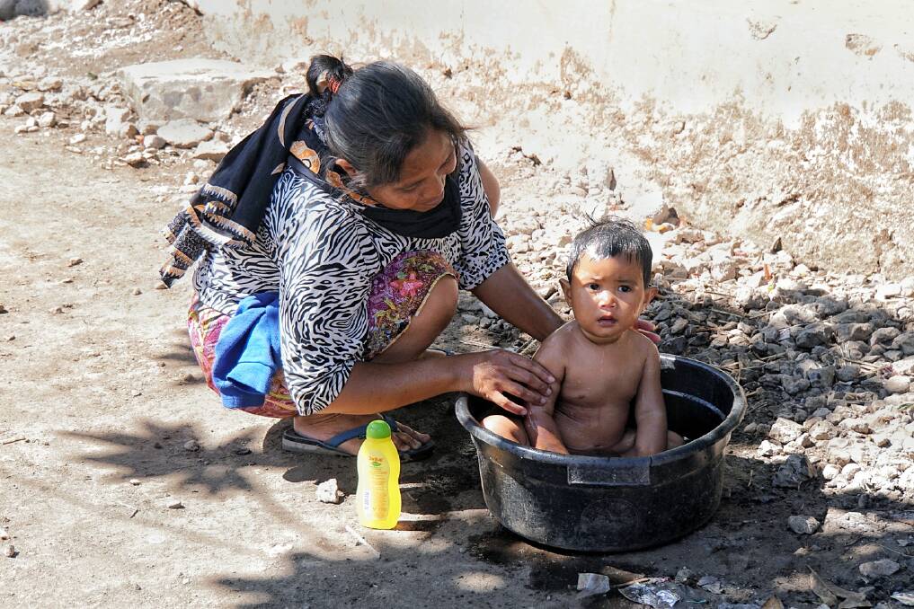 A mother bathes her daughter in a bucket after their home in Sembalun Bumbung was destroyed by the Lombok earthquake. Photo: Amilia Rosa