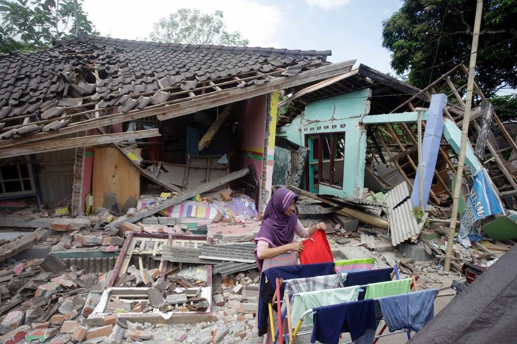 A woman dries her laundry in front of her home shortly after the quake in West Lombok. Photo: AP