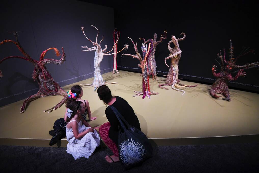 Visitors look at Aboriginal artwork at the 'Songlines: Tracking the Seven Sisters' exhibition at the National Museum of Australia. Photo: AAP
