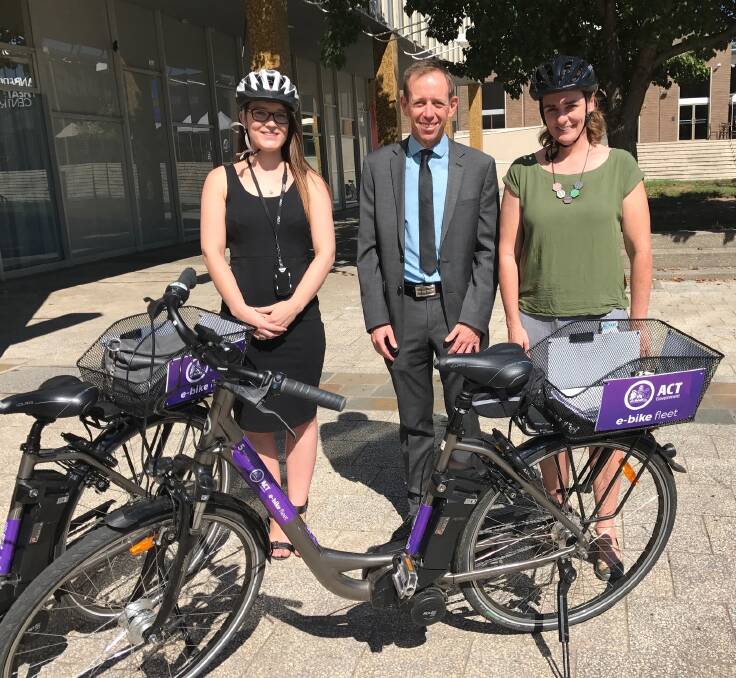 ACT Greens MLA Shane Rattenbury (centre) stands with two staff and one of the government's eight electric bikes. Photo: Supplied