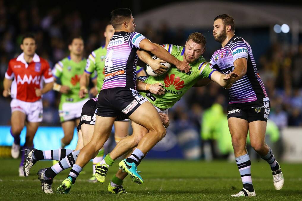 Elliott Whitehead of the Raiders is tackled by Gerard Beale and Wade Graham of the Sharks. Photo: Getty