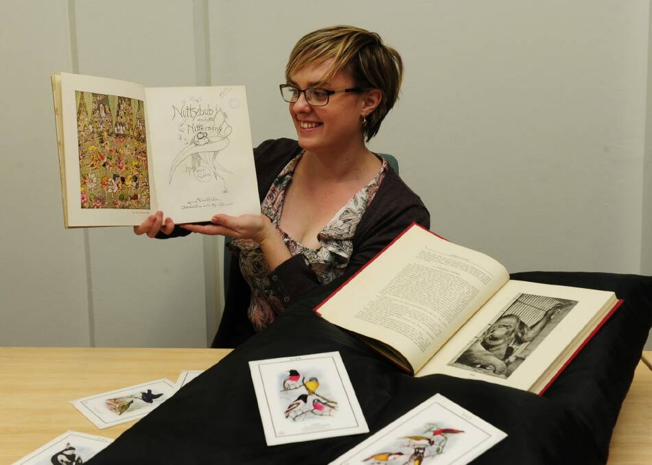 Researcher Michelle Hughes with items accompanying the Waterhouse artworks at the National Archives of Australia in Canberra, including a book excerpt about Mollie the smoking orang-utan. Photo: Melissa Adams