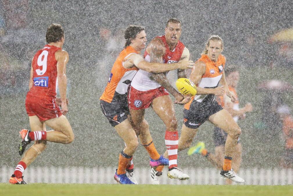 Lance Franklin is nabbed by Callan Ward during a downpour at Blacktown on Friday night. Photo: Getty Images