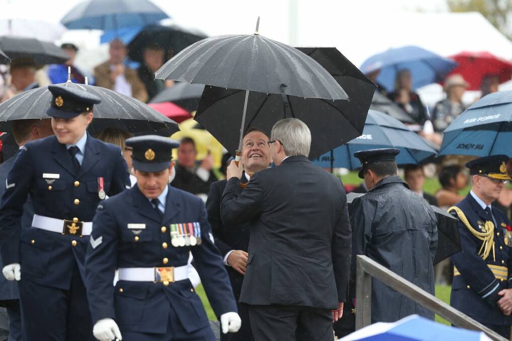 Bill Shorten and Kevin Rudd share an umbrella as they wait for the Prince of Wales and the Duchess of Cornwall to arrive at the Remembrance Day ceremony at the National War Memorial. Photo: Andrew Meares