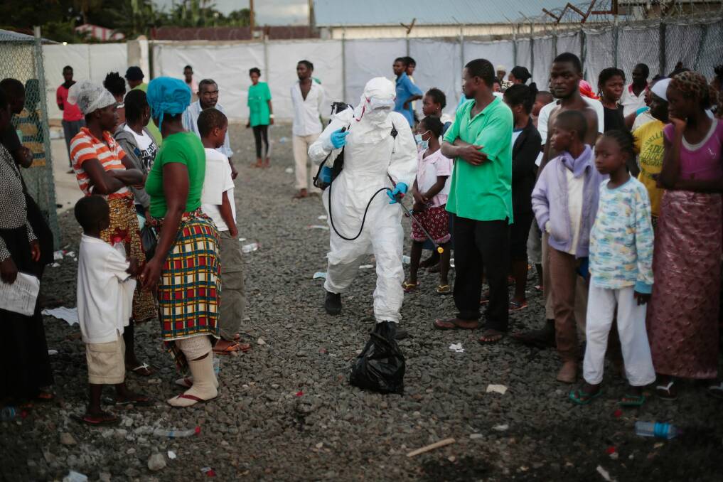 A medical worker sprays people being discharged from the Island Clinic Ebola treatment center in Monrovia, Liberia. Photo: Jerome Delay