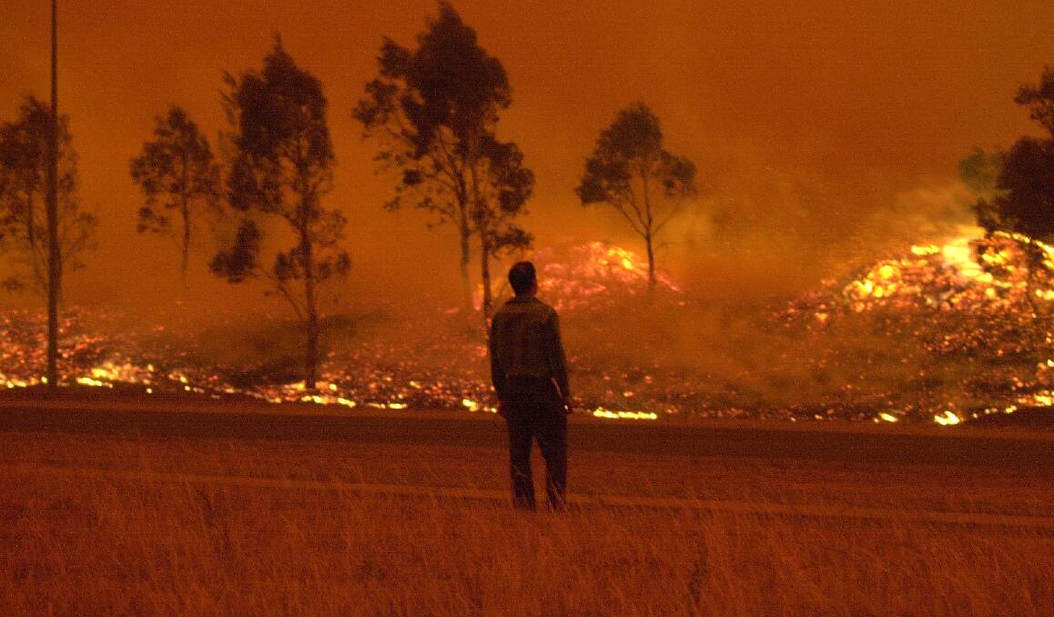 A residents watches grassland burn in Gordon during the devastating 2003 Canberra bushfires. Photo: Lannon Harley