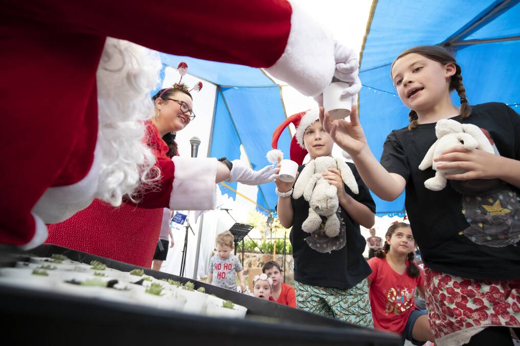 Nikki Randall watches as Santa hands out succulents as gifts to children, to cut down on plastics overconsumption. Photo: Sitthixay Ditthavong