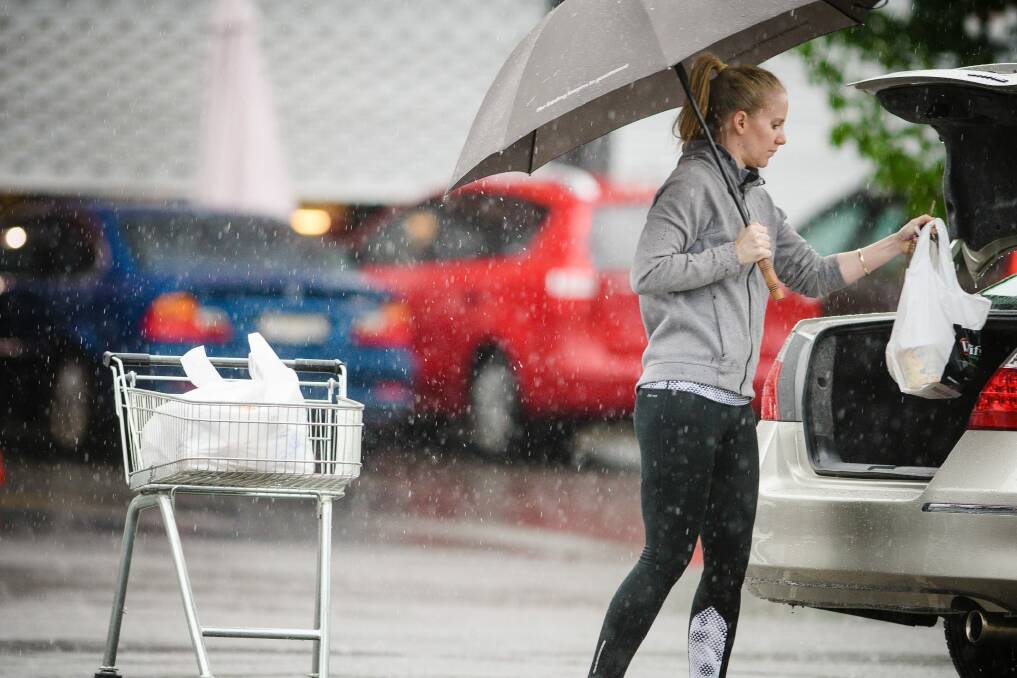 A shopper loads her car in the rain at Fyshwick markets. Photo: Sitthixay Ditthavong